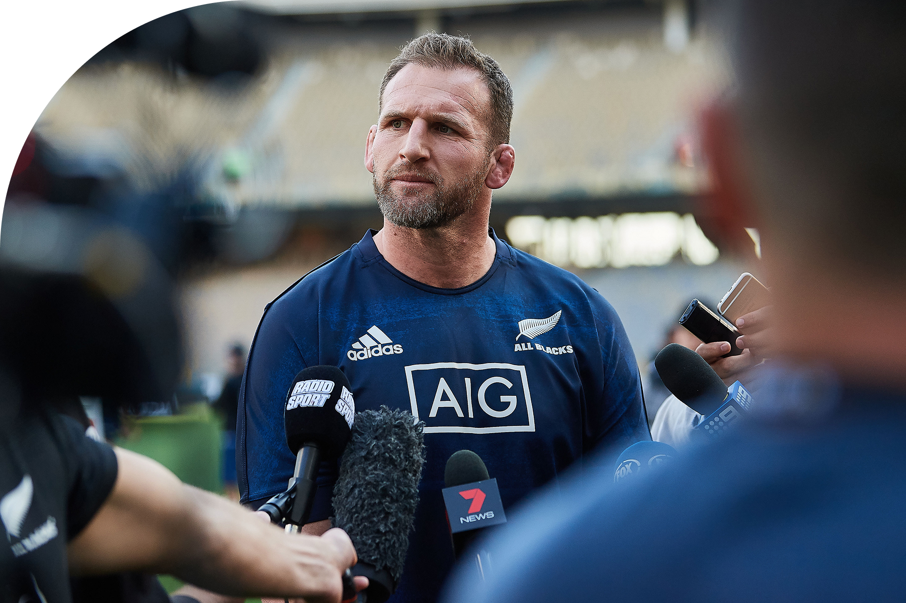 Kieran Read in All Blacks training kit, speaking to reporters behind a cluster of microphones