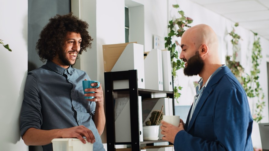 Still from the course video: two colleagues talking over coffee at work