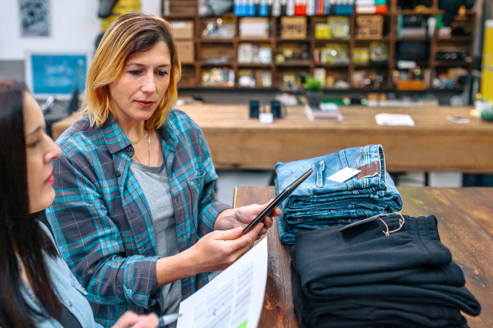 A store manager going through stock with a team member on the shop floor, tablet in hand
