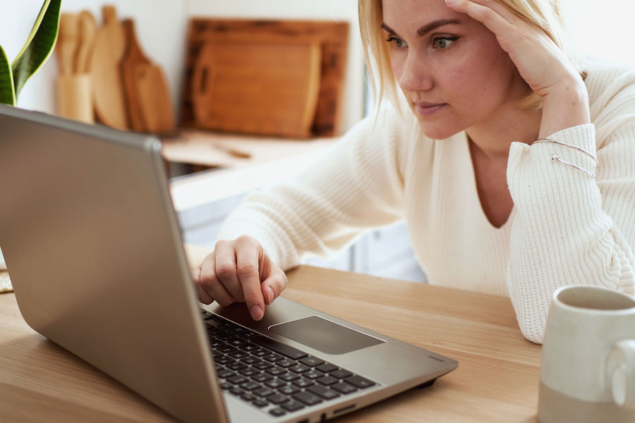A manager sitting with a difficult conversation she's been putting off, thinking it through at her laptop